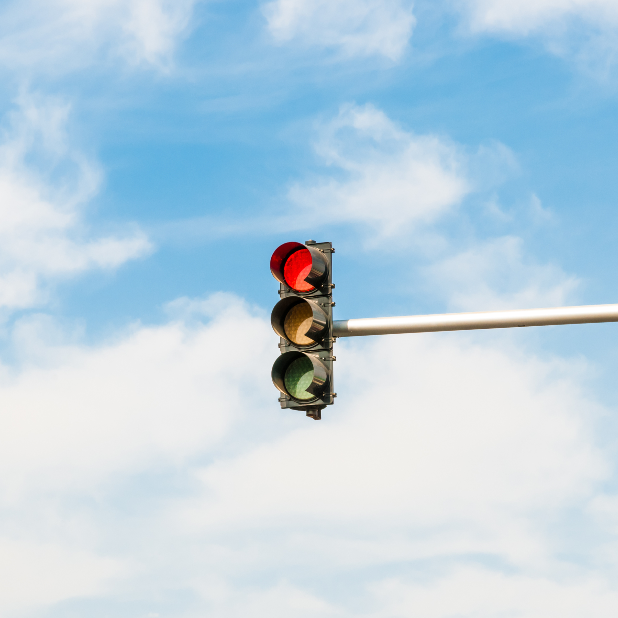 Bild einer Ampel mit blauem, bewölktem Himmel